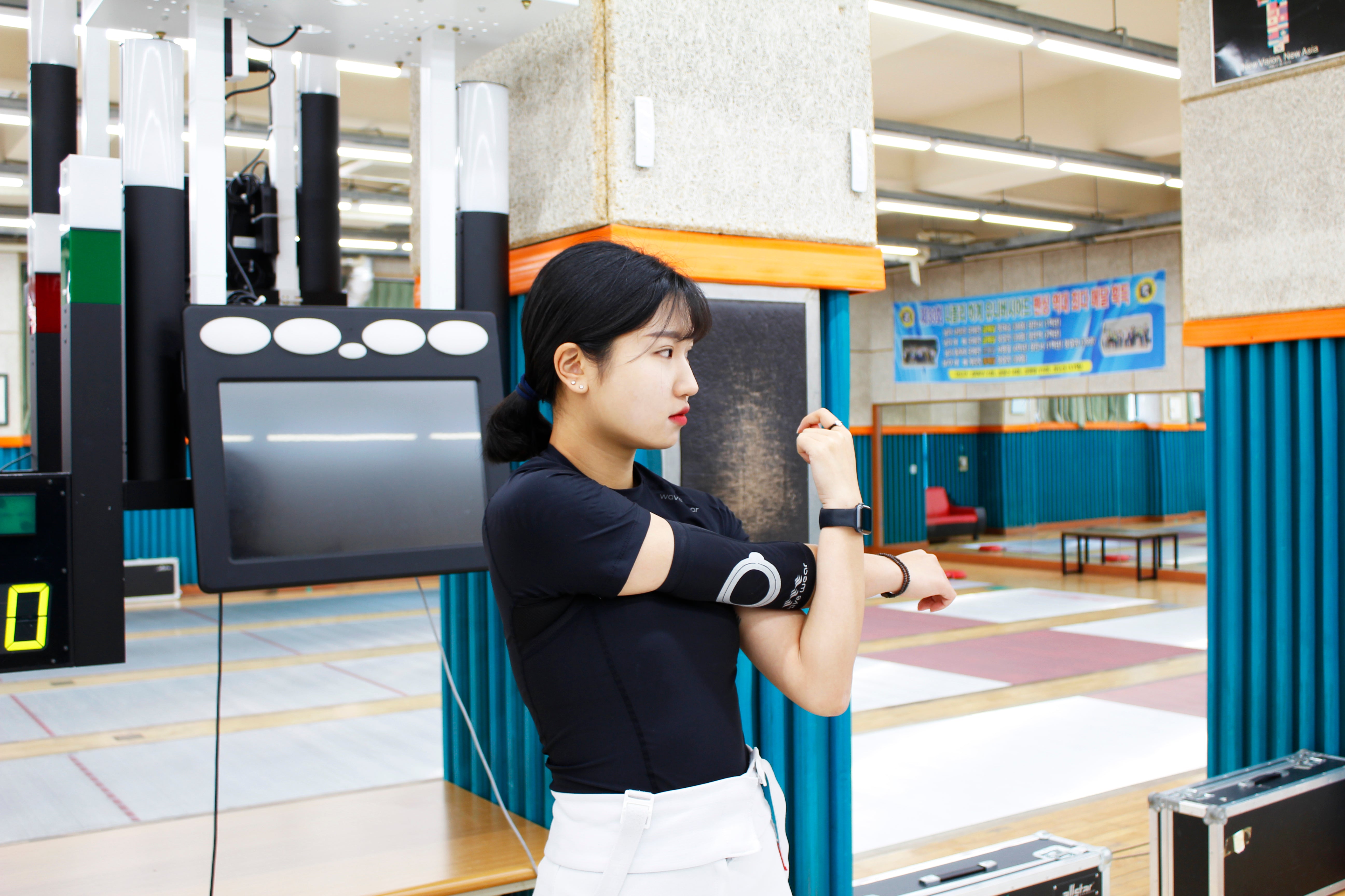 Woman wearing elbow sleeves preparing for fencing in an indoor gym featuring Park Ju-mee fencing journey
