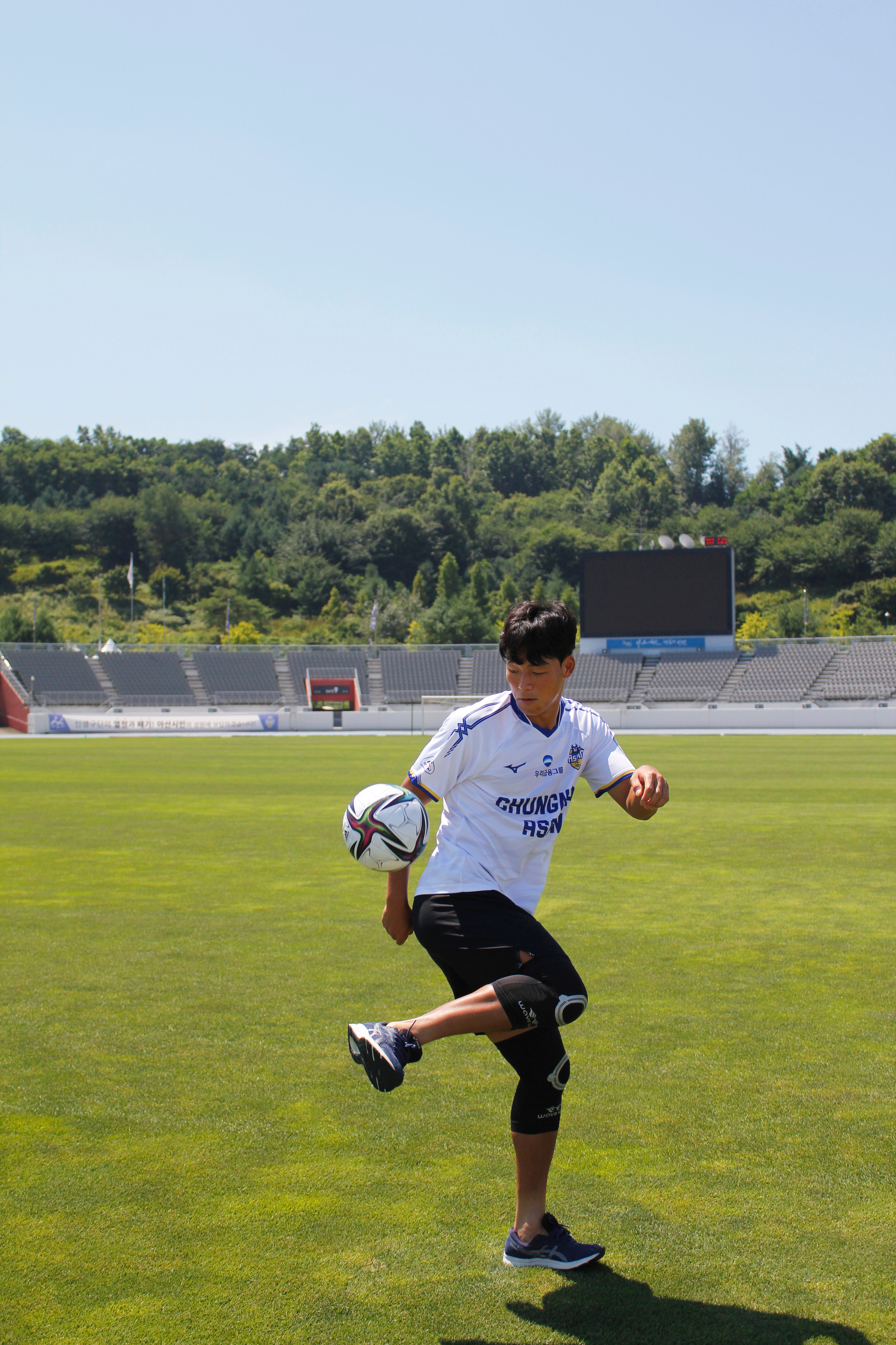 Young soccer player wearing soccer knee support for athletes practicing ball control on a grassy field