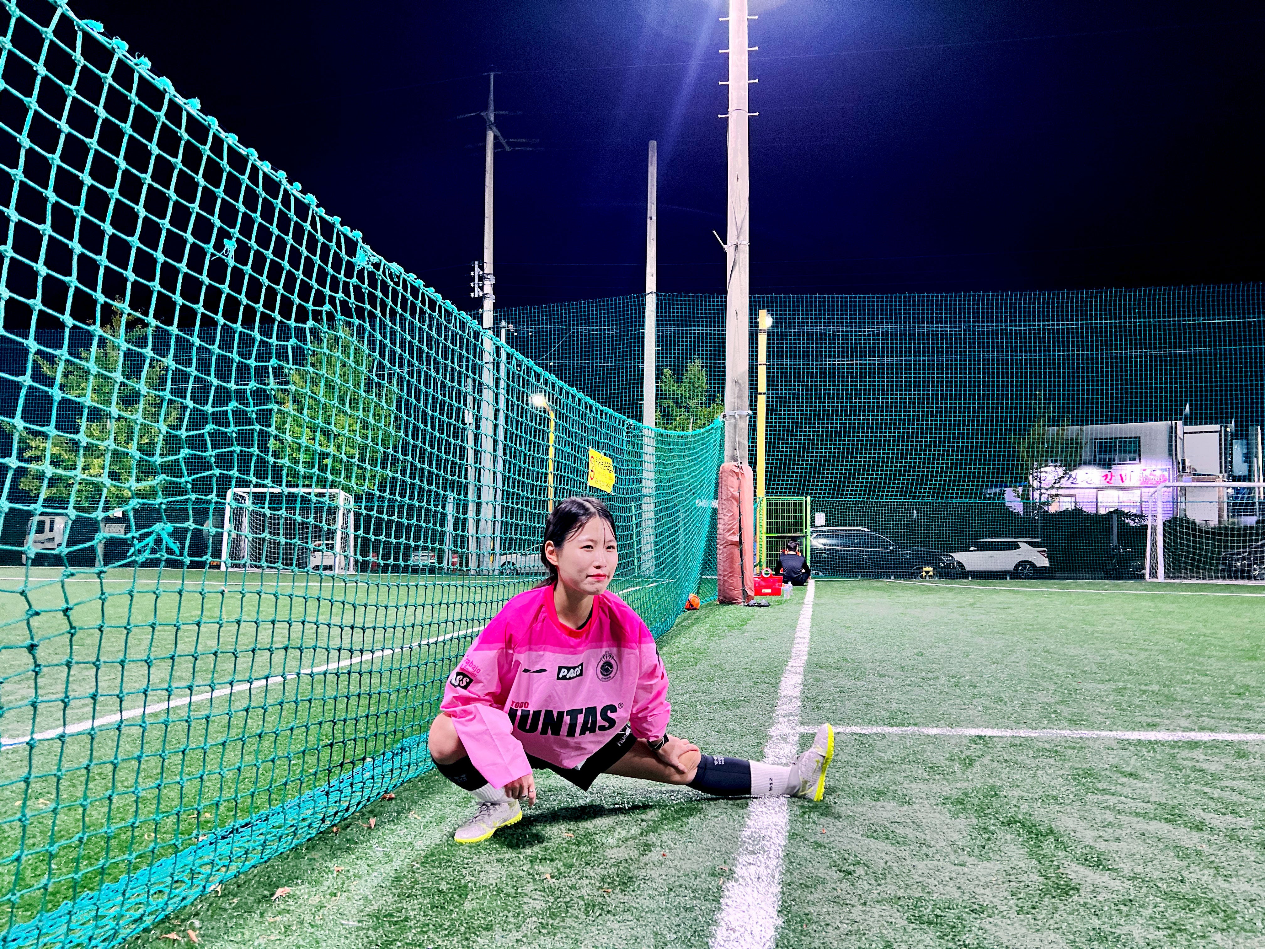 Young futsal player stretching on artificial turf at night for futsal training tips session