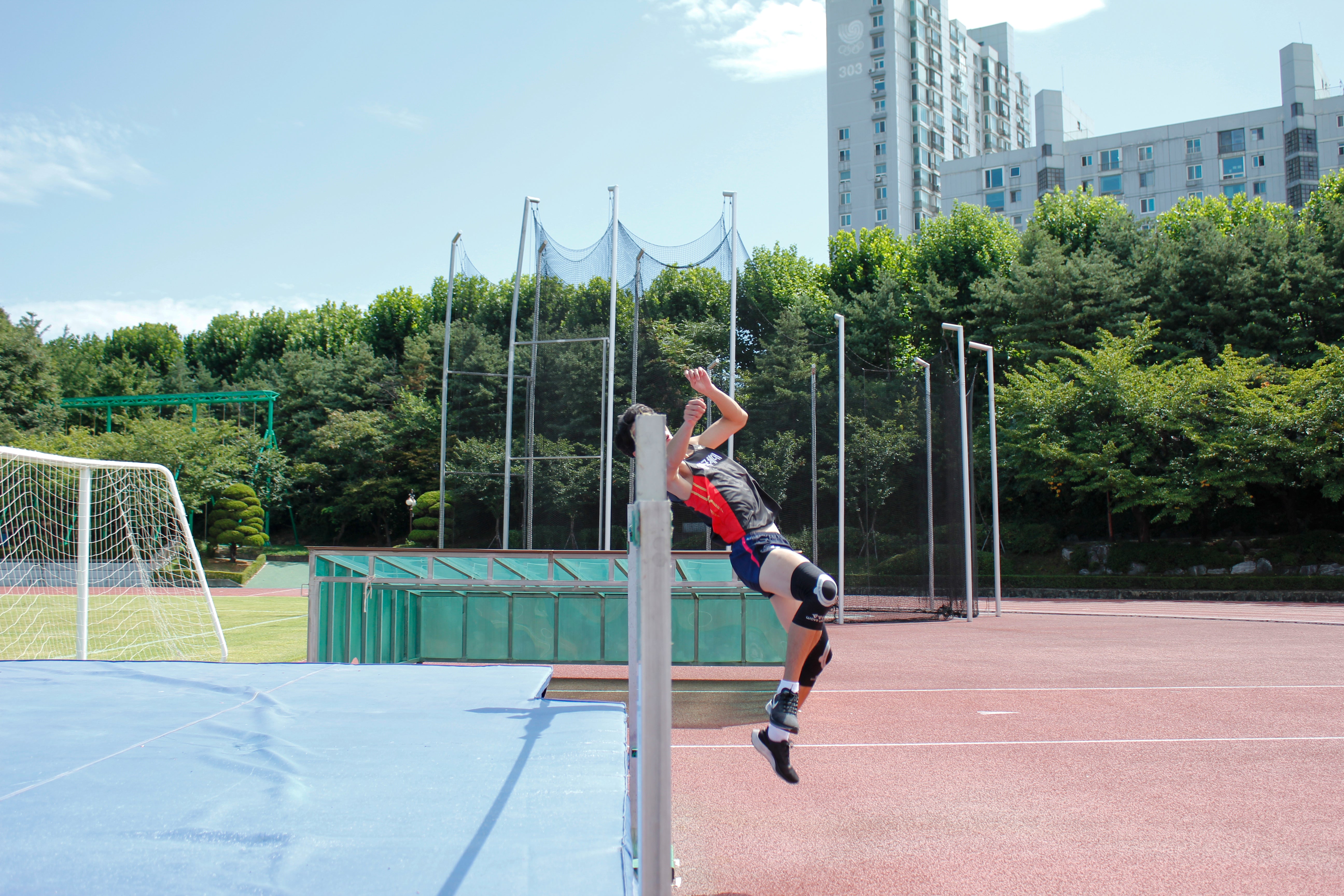 Athlete wearing track and field compression gear with knee sleeve K2 performing a high jump on outdoor track