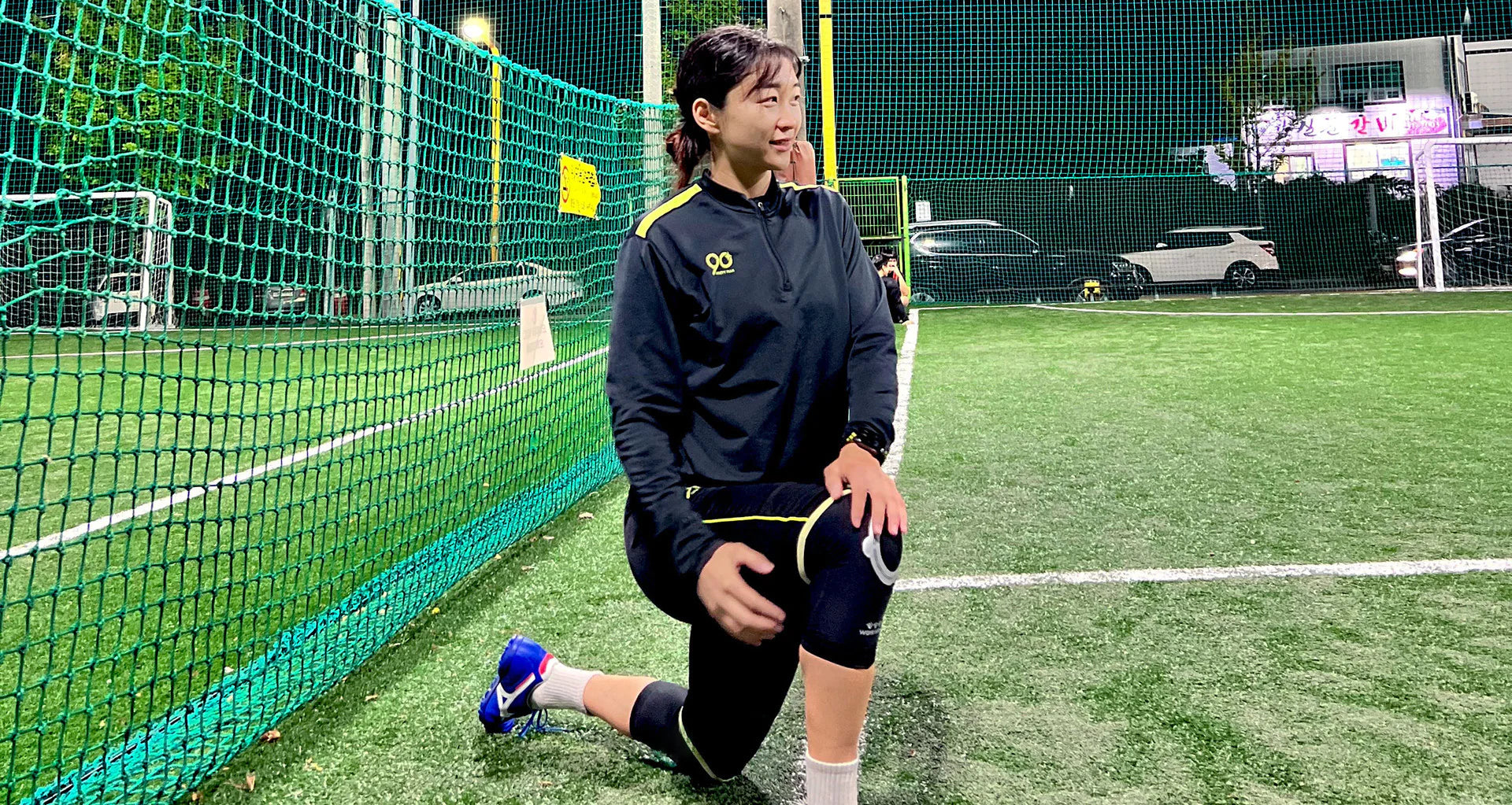 Yang Ji-Eun training routine with athlete stretching on artificial turf near net in outdoor sports field