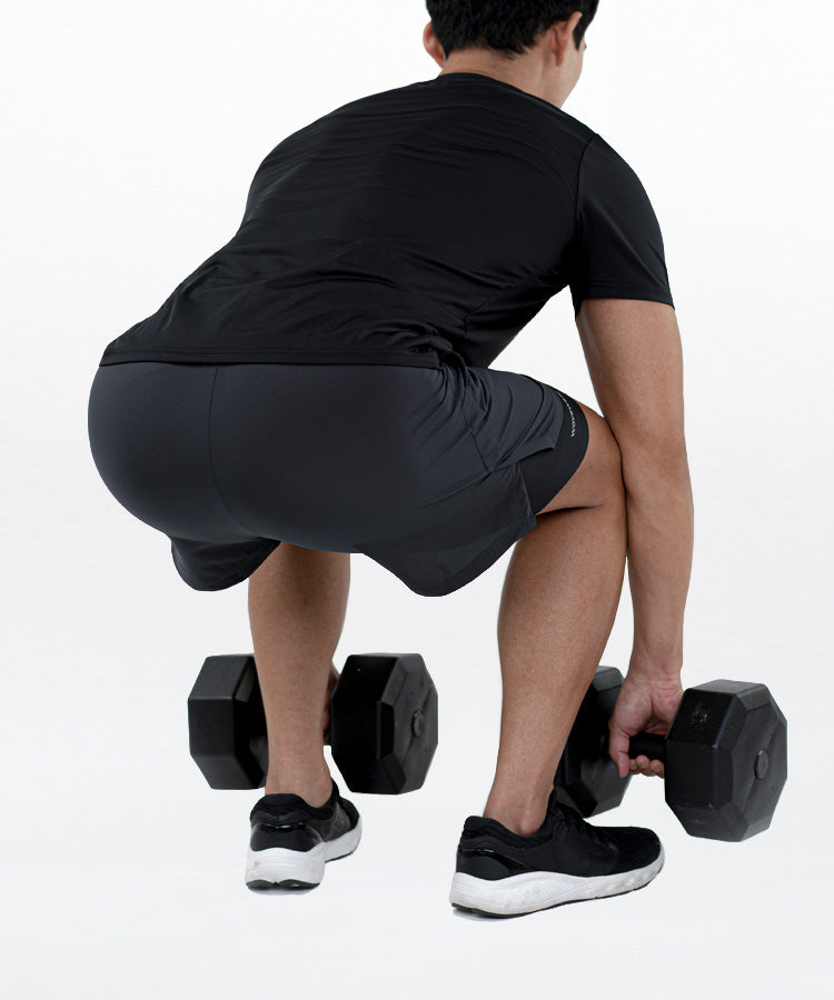 Man wearing WaveWear compression running shorts for men lifting dumbbells during workout