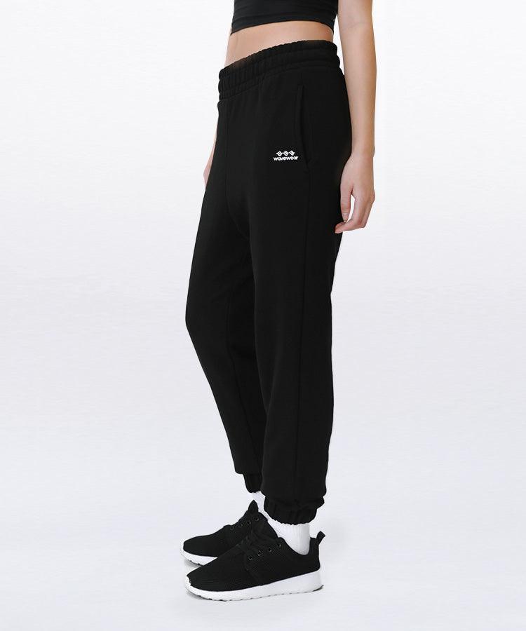 Jogger confortable All Day, vue de côté sur mannequin en noir montrant le logo WaveWear, la ceinture élastique et les chevilles à revers sur fond blanc