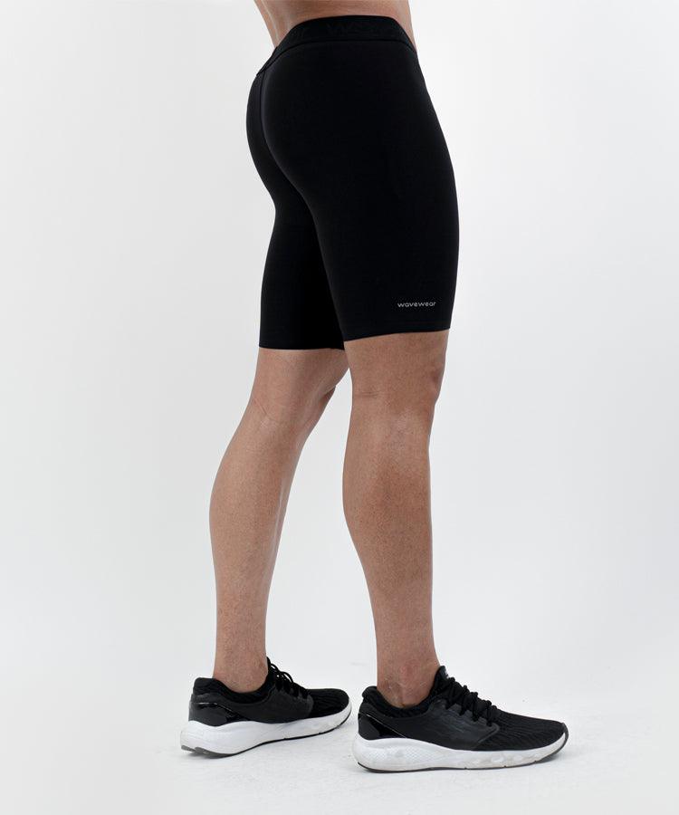 WaveWear men's compression shorts in black worn by male model with black athletic shoes