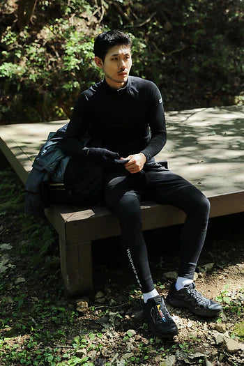 Man wearing black fleece taping compression wear benefits outfit sitting on wooden bench outdoors