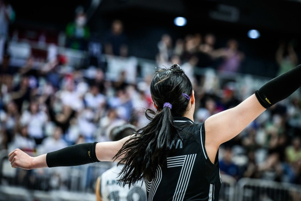 Athlete performing pre-game rituals for athletes with arms raised in a crowded sports arena