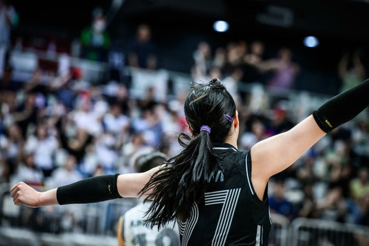 Athlete performing pre-game rituals for athletes with arms raised in a crowded sports arena