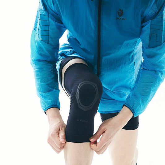 Athlete wearing taping compression wear for athletes on knee under blue sports jacket preparing for workout