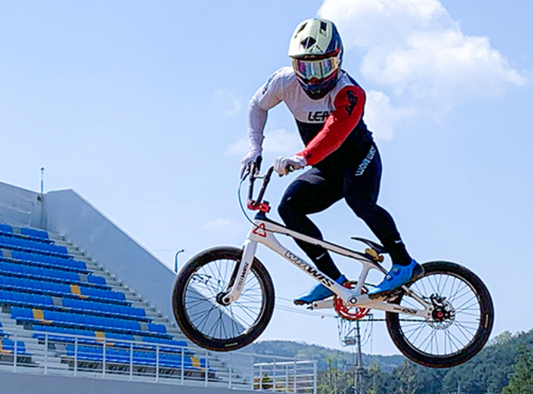National BMX athlete Joon-Soo Yoon performing a high jump during a race while wearing WaveWear performance gear.