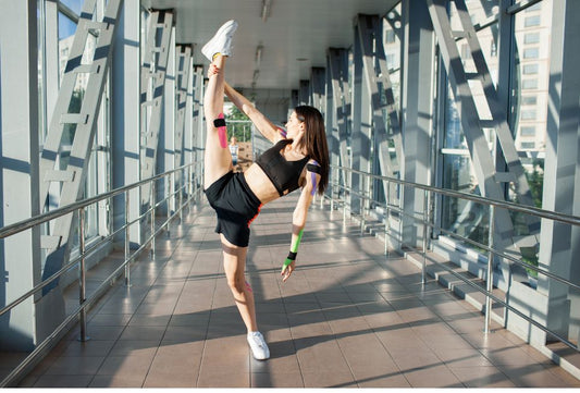 Athlete stretching leg with kinesiology tape applied on knee and arm demonstrating kinesiology tape pros and cons