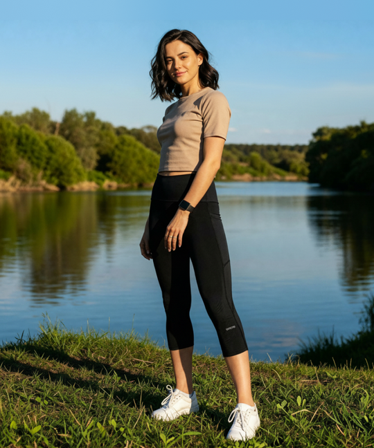 Woman wearing CY20 3/4 Capri Compression Leggings in black lifestyle outdoor shot by lake with white sneakers