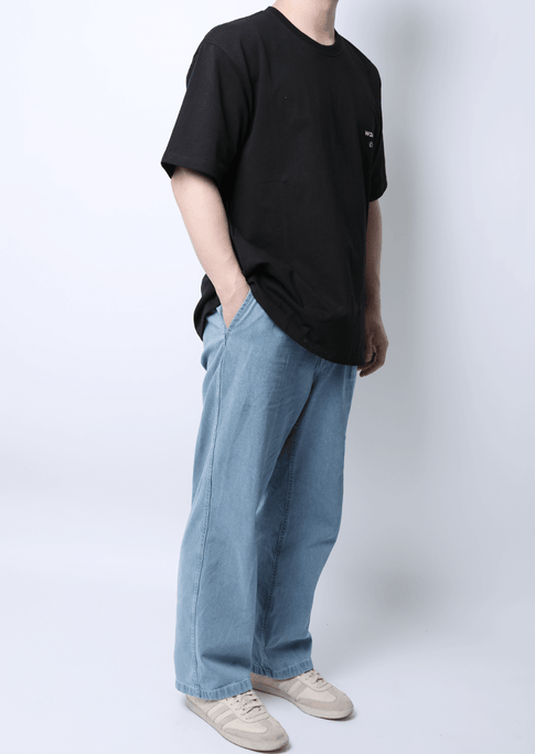 Man wearing WaveWear Blue Moon performance shirt in black with light blue jeans and beige sneakers