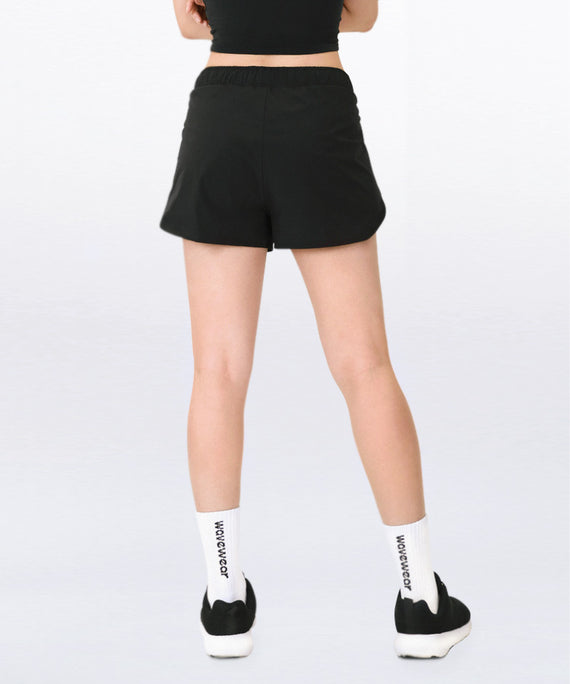 WaveWear black compression workout shorts for women shown from back with branded white socks and black shoes