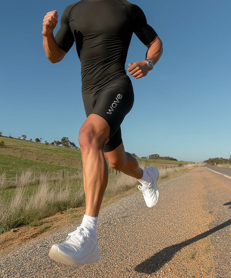Man running outdoors on a road wearing WaveWear SL20 Endurance Compression Shorts in black athletic action shot