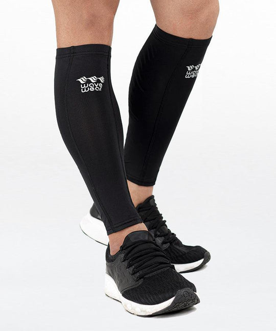 WaveWear C2 Calf Recovery Kinesiology Compression Sleeves in black front view on both legs in standing pose with WaveWear logo