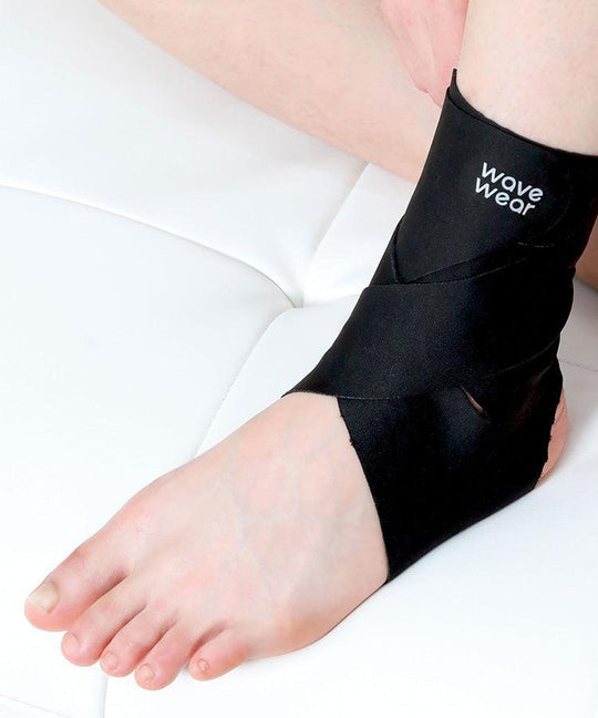 Black A1 ankle X-strap supporter close-up on ankle, resting position on white surface