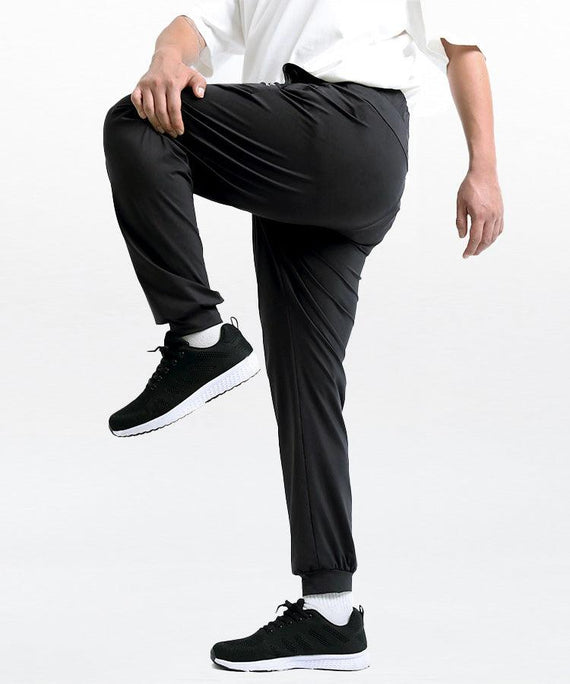 WaveWear black compression joggers for men shown in active stretch pose with white sneakers