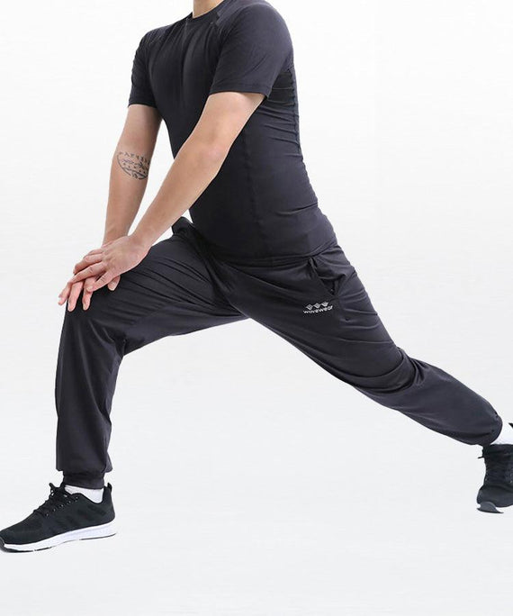 WaveWear black compression joggers for men worn by a person stretching in athletic pose