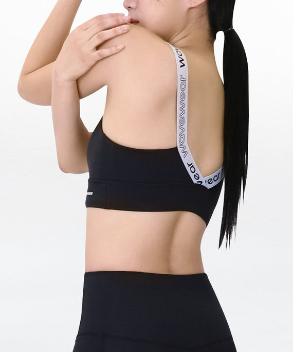 WaveWear black compression sports bra with branded white straps worn by woman in side pose